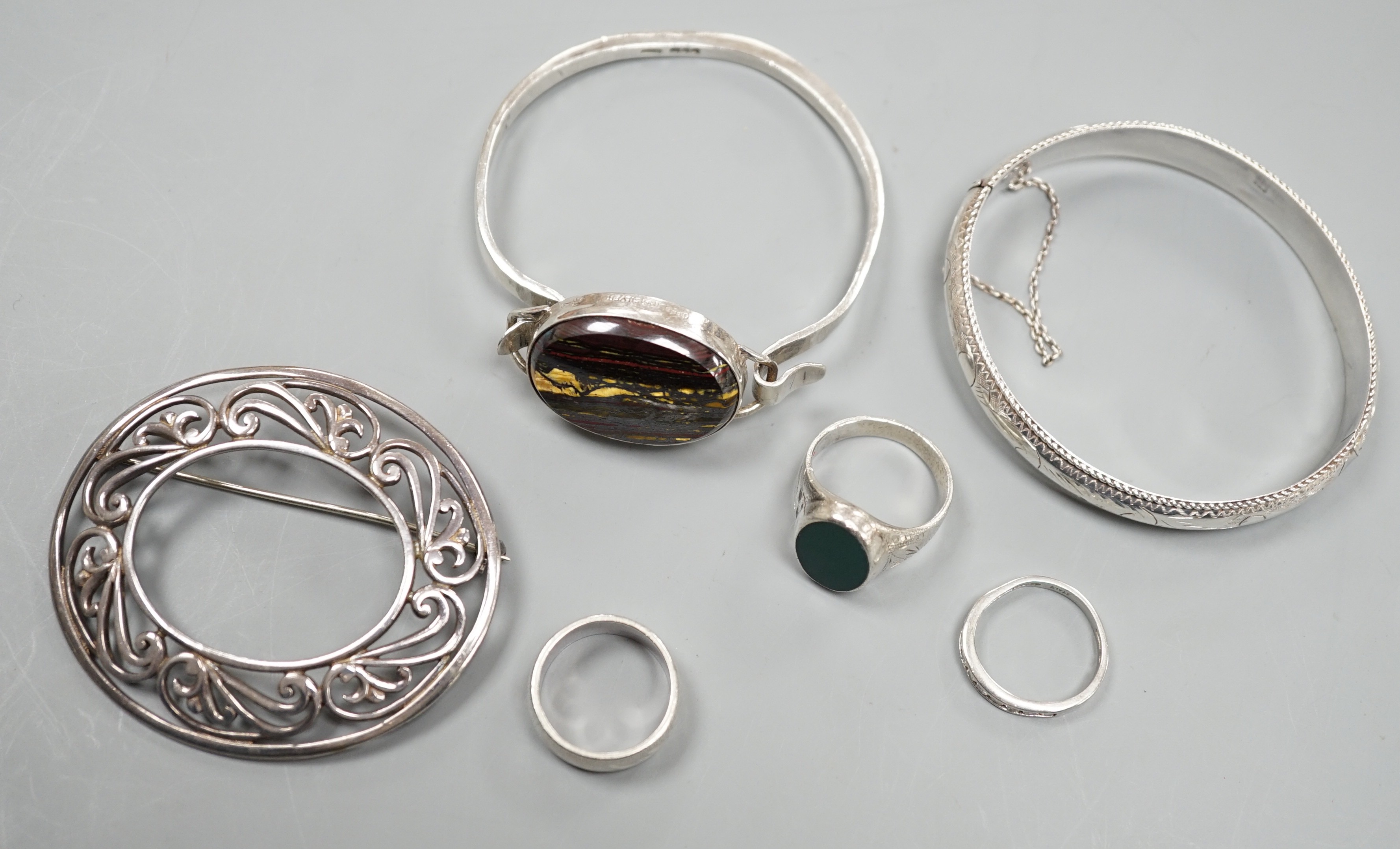 A 1970's silver and oval quartz set bangle, two other white metal bangles and three assorted rings.